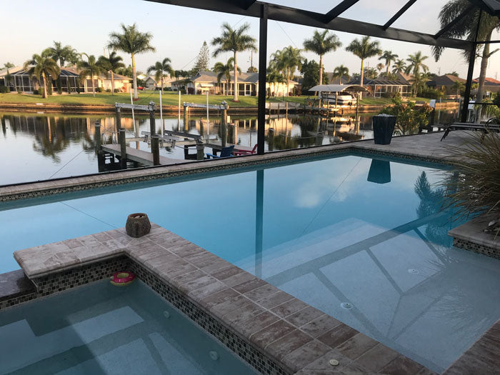 Screened-in swimming pool near lake.