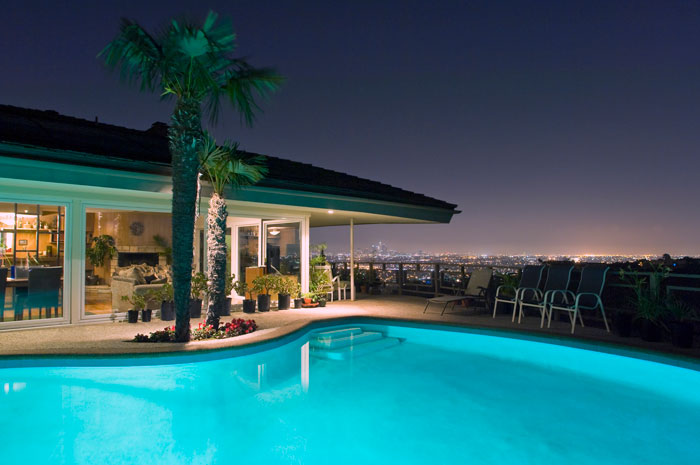 Lit up swimming pool at night with a view of the city.