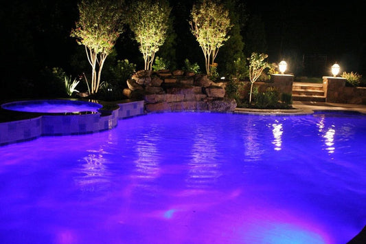 Pool illuminated by blue-violet LED color-changing pool lights at night