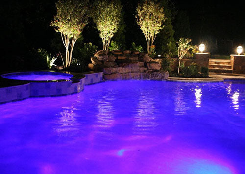 Pool lit up at night with trees.